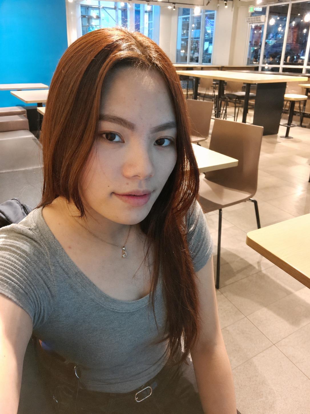 Portrait of Shenlie Mae J. Roldan in a grey t-shirt, sitting in a cafe with auburn-tinted hair.